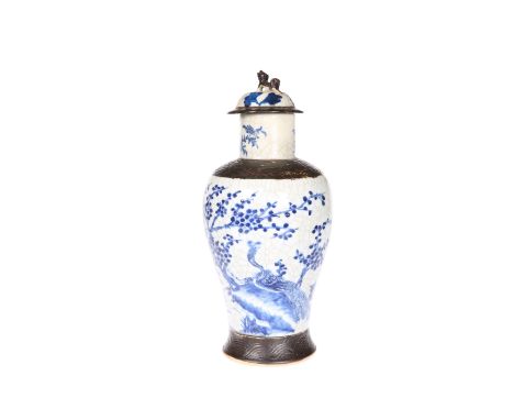 A CHINESE CRACKLE GLAZED BLUE AND WHITE VASE AND COVER, 19TH CENTURY, of baluster form, painted with prunus trees, chrysanthe