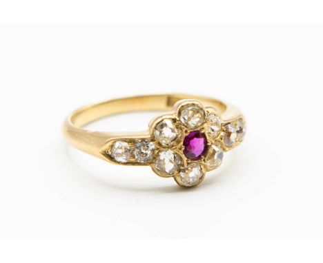 A LATE 19TH CENTURY RUBY AND DIAMOND RING, the single round cut ruby highlight set to the centre of a flower head shaped moun