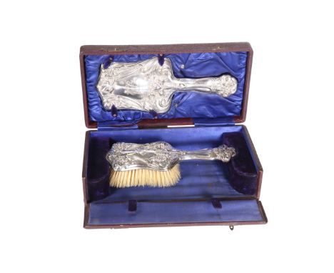 A CASED EDWARDIAN SILVER-MOUNTED HAND MIRROR AND BRUSH SET, BIRMINGHAM 1904, each decorated with Art Nouveau whiplash flowers