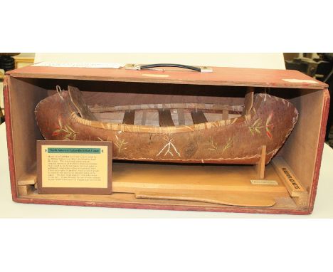 A CASED SCALE MODEL OF A NORTH AMERICAN INDIAN BIRCH BARK CANOE, with paddles and embroidered detail, with educational notes.