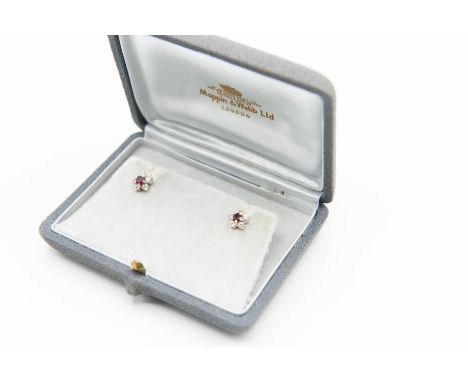 A PAIR OF RUBY AND DIAMOND STUD EARRINGS BY MAPPIN AND WEBB, the single round cut ruby set simply within a surround of five b