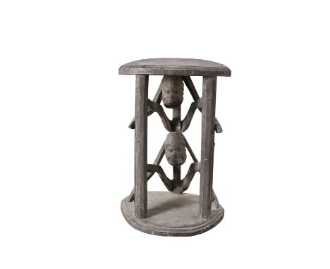 A CAMEROON BAMILEKE FIGURAL STOOL, the circular top raised by two stacked figures. 46cm high, 31cm wide