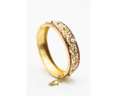 A RUBY AND CULTURED PEARL BANGLE, the cut-out mount of floral and foliage details set throughout with graduating cultured pea