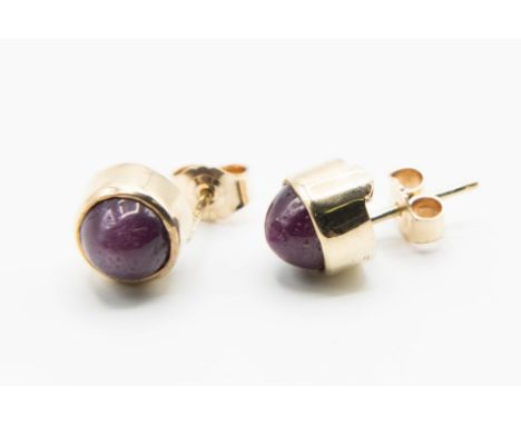 A PAIR OF STAR RUBY EARRINGS, the round cabochon cut star rubies each collet set on post and scroll fittings. Total weight 4.