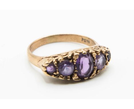 A LATE VICTORIAN 9CT YELLOW GOLD AMETHYST SET RING, the five graduating oval cut amethysts set in a pierced and scroll detail