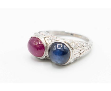 A SAPPHIRE AND RUBY RING, the round cabochon cut sapphire and oval cabochon cut ruby each set in a high elaborately pierced f