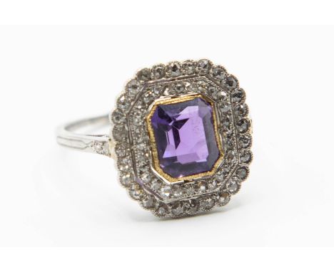 AN AMETHYST AND DIAMOND SET DRESS RING, the fancy cut amethyst collet set within a double scalloped edge surround set through