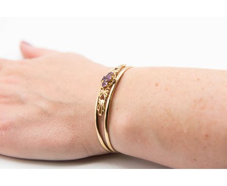 A 9CT YELLOW GOLD AND AMETHYST TORQUE BANGLE, the split design mount applied with elaborate scrolling metal work detailing, s