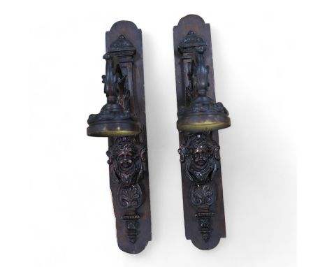 A pair of French bronze wall lights, c.1900 decorated with masks, mounted on wooden plinths, 54cm high. Condition - poor to f