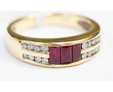 A ruby and diamond 18ct yellow gold band ring, three baguette cut rubies to centre small round brilliant cut diamonds each si