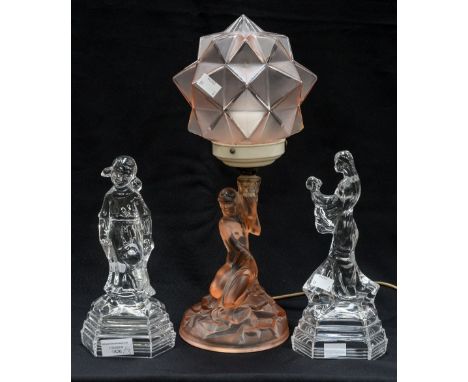 An Art Deco pink glass table lamp with geometric shade, the base moulded as a female nude, together with two clear pressed gl