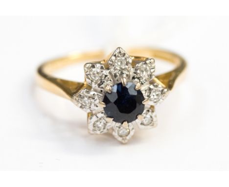 A sapphire and diamond cluster ring on 18ct gold bangle, the central brilliant cut sapphire surrounded by eight illusion set 
