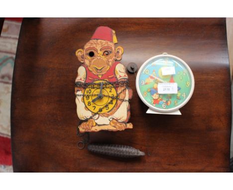 An early 20th Century wall clock in the form of a clown, complete with weight and pendulum together with a child's alarm cloc