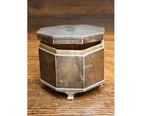 A George V silver Art Deco style octagonal table top box with hinged cover, engine turned decoration, on four volute supports