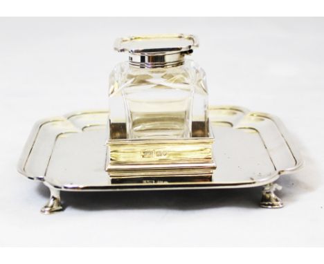 A George V silver and cut glass inkstand, by Mappin and Webb, the square glass inkwell with shaped dished cover on a fitted t