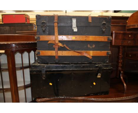 A large black painted tin trunk, together with a wooden bound travelling trunk