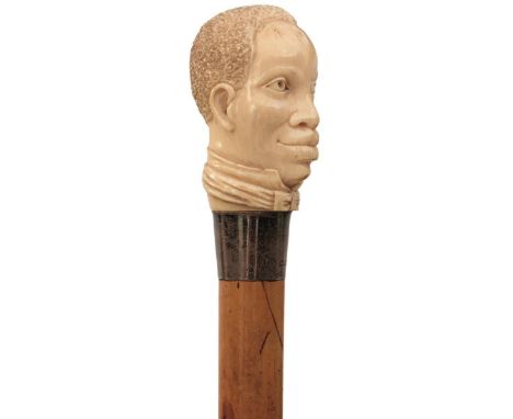 AN EARLY 20TH CENTURY SWORD STICK, the ivory pommel carved as the head of an Afro-American, silver collar hallmarked London 1