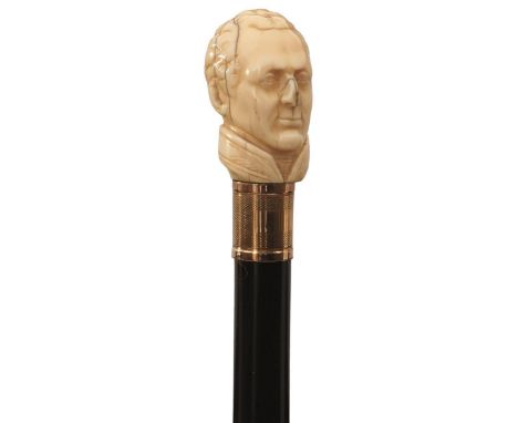 A MID 19TH CENTURY WALKING STICK, the ivory handle carved as the head of the Duke of Wellington (nose chipped), above gold co