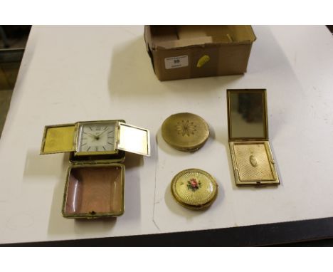A box containing three various compacts and a travelling alarm clock 