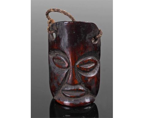 18th Century African bone pendant, possibly Lega, the carved bone section with a wide eyed face, 6.5cm high