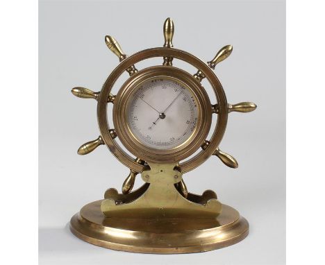 Early 20th Century brass desk barometer, in the form of a ships wheel, with a silvered dial on a oval base, 20cm high
