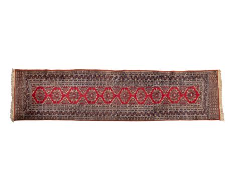 An Indo-Persian runner, the wine hooked hexagonal field with a row of geometric stepped medallions, enclosed by a main indigo