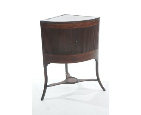 A Georgian mahogany corner washstand
The rectangular hinged top concealing three circular apertures above a pair of bowfront 