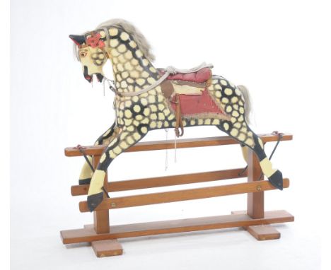 A dapple grey rocking horse
The pine frame supporting the horse, featured with tan leather bridle and saddle, fitted with red