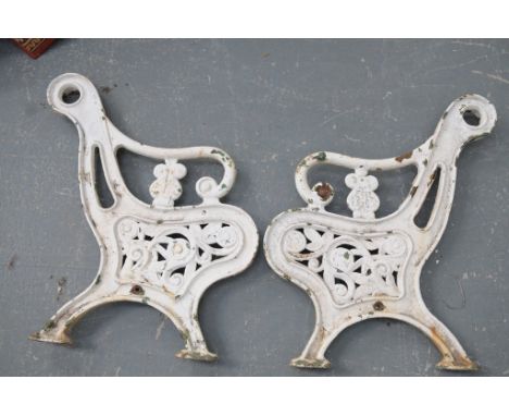 A pair of white painted cast iron garden bench ends
Each of typical form with swept scroll back and pierced foliate sides, ra