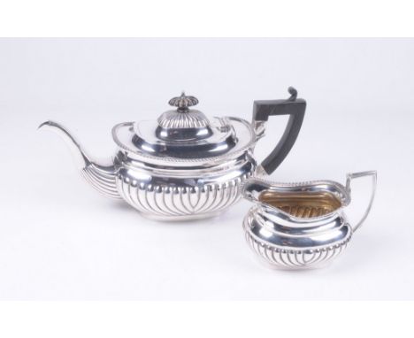 A Victorian silver tea pot and milk jug
Of ovoid form, with an embossed fluted lower body, an applied gadrooned border, the d