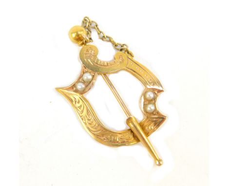 A shield pin, with floral scroll design, set with seed pearl, engraved to rear D-N 17.11.94, yellow metal, unmarked, 3cm H, 1