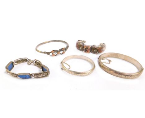 Five bracelets and bangles, comprising a hinged silver bangle of plain design, a floral silver child's bangle, an eastern sty