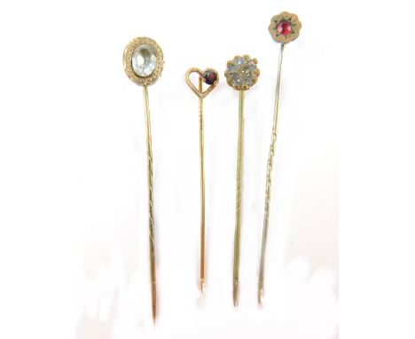 Four stick pins, comprising an oval paste stone set pin, unmarked, a 9ct garnet set heart pin, and two paste stone set gilt p