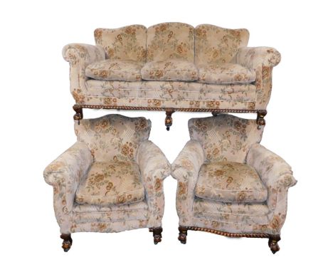 An early 20thC oak three piece suite, upholstered in floral patterned fabric, raised on ball &amp; claw feet, on castors, com