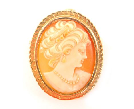 An oval shell cameo brooch, bust portrait of a lady wearing a pearl necklace, set in yellow metal, with pendant link attachme