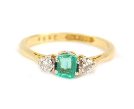 An 18ct gold emerald and diamond three stone ring, the rectangular cut emerald between two brilliant cut diamonds, size L, 2.