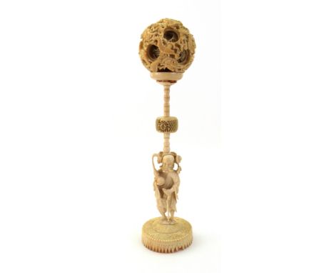 A Chinese carved ivory concentric ball on stand, supported by a figure holding a staff and double gourd flask, 19th century, 