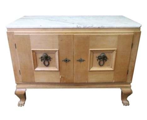 A 1920's beech dwarf cabinet, the rectangular marble top above a pair of sunk panelled doors with bronzed mounts enclosing a 