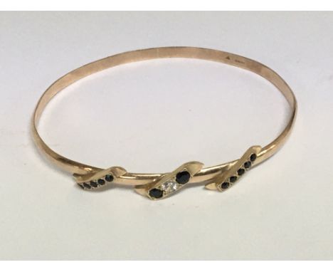 A 9carat gold bangle set with a diamond and sapphire. Weight 11g