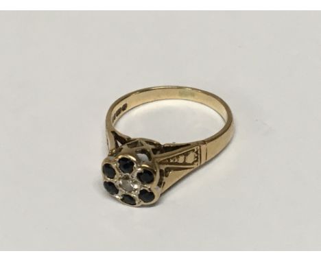 A 9carat gold ring set with a pattern of blue sapphire and with a small central diamond. Weight 2.9g