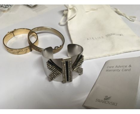 A 9carat gold bangle metal core a designer Swarovski crystal bracelet with pouch and paperwork and one other bangle (3)