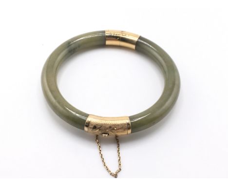 A jade bangle with 14k gold mounts. Approximately 7cm diameter.Postage A