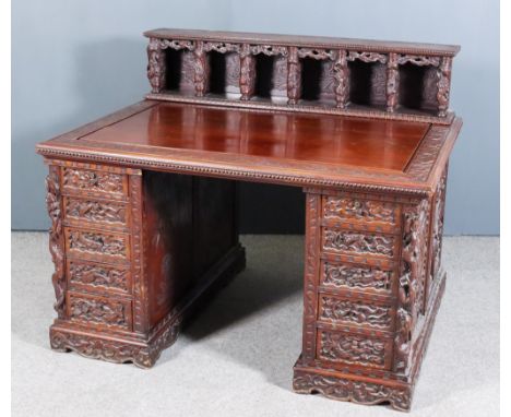 A Chinese Panelled Hardwood Rectangular Kneehole Desk, the whole bodly carved with exotic birds, dragons, cloud motifs and ba