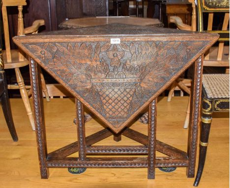 A late 19th century oak corner drop leaf table, carved with stylised flowers and raised on a chip carved square support, 85cm