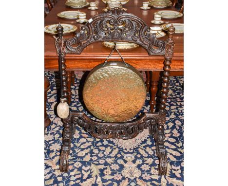 An early 20th century carved oak framed dinner gong with bobbin turn supports, having beater and hammered brass gong, 70cm by