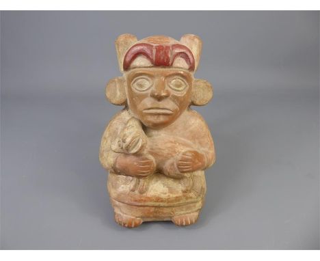 An Ancient Peruvian Terracotta Mochica Flask, the two-toned moulded globular flask depicts a seated man clasping a dog, with 