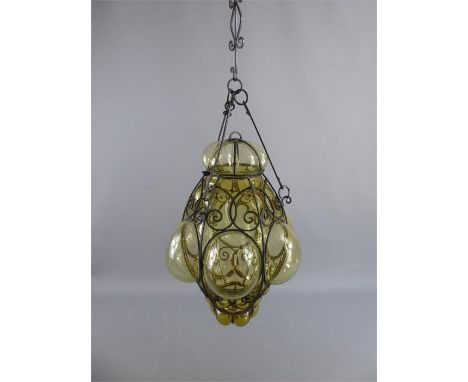 An Arts and Crafts Wrought Iron Lantern. The lantern has the original hanging with light made in two sections of pale amber g