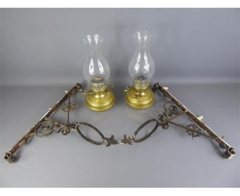 A Pair of Victorian Oil Lamps, upon wall-mounted brackets, each bracket with scroll detail, supporting a brass lamp reservoir