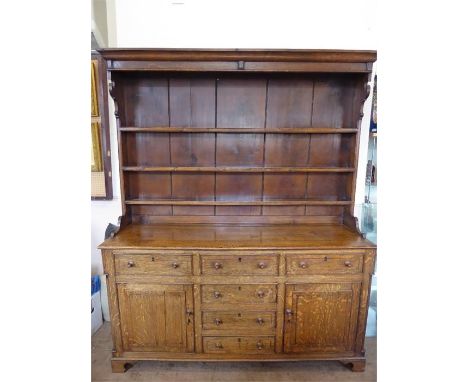 An Antique Oak Dresser, the dresser having shelved back over base, three plate rests, four central drawers flanked by two cup