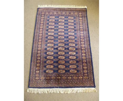 A Middle Eastern Wool Carpet, the carpet having a navy blue background with burgundy and cream medallions and geometric patte